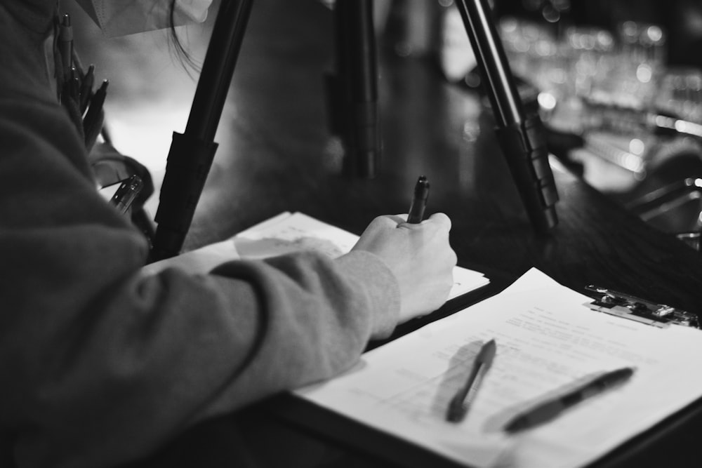 grayscale photo of man writing on paper