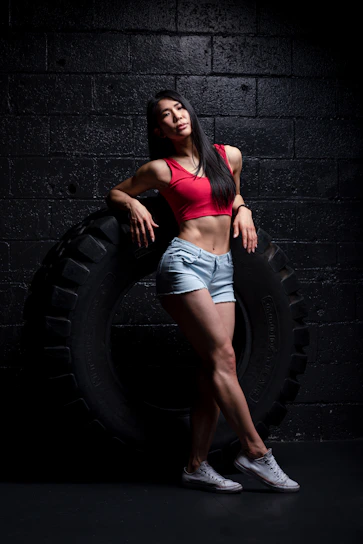 Fit woman in bold red compression streetwear posing confidently against a dark gym background.