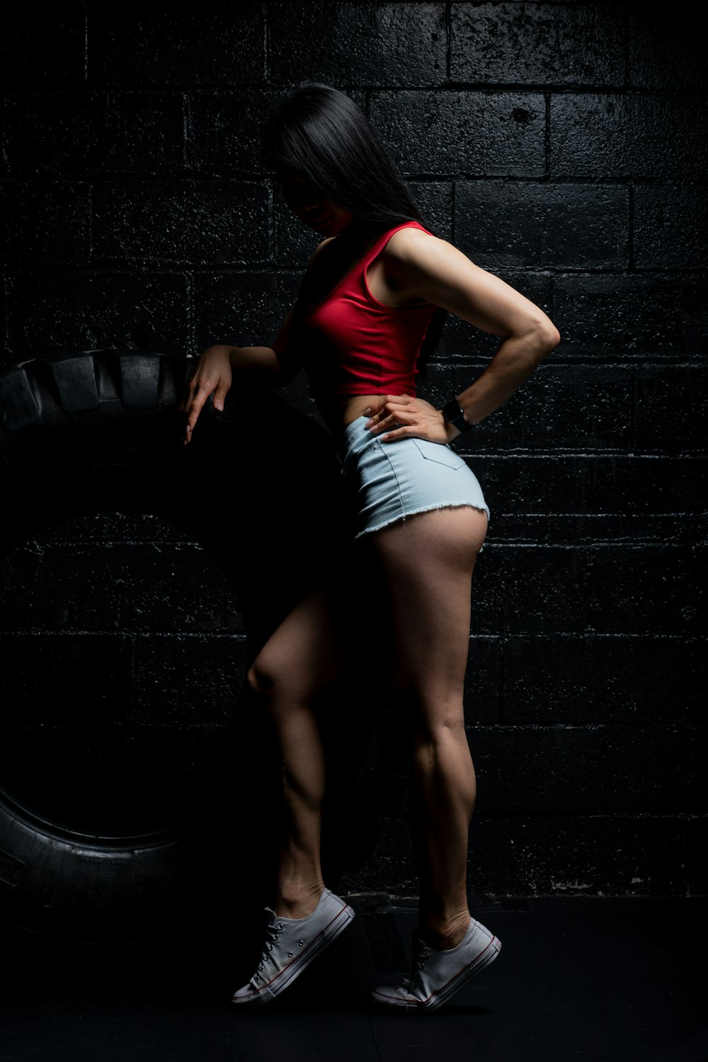 woman in red tank top and white daisy dukes standing on black round tire