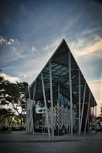 white and gray building near green trees under white clouds during daytime