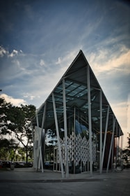 white and gray building near green trees under white clouds during daytime