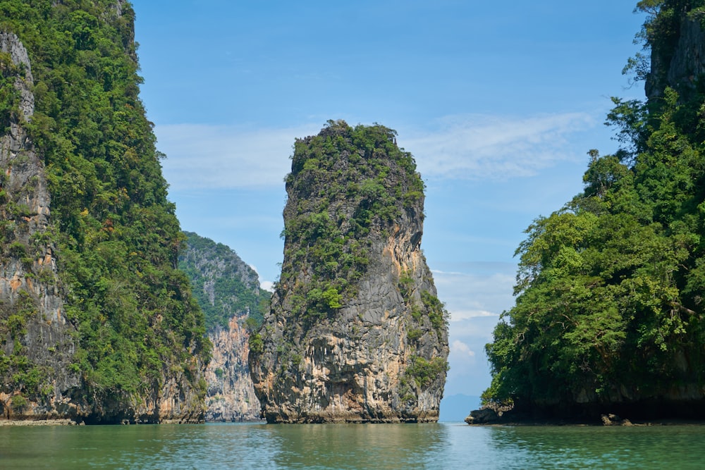 green and brown rock formation on body of water under blue sky during daytime