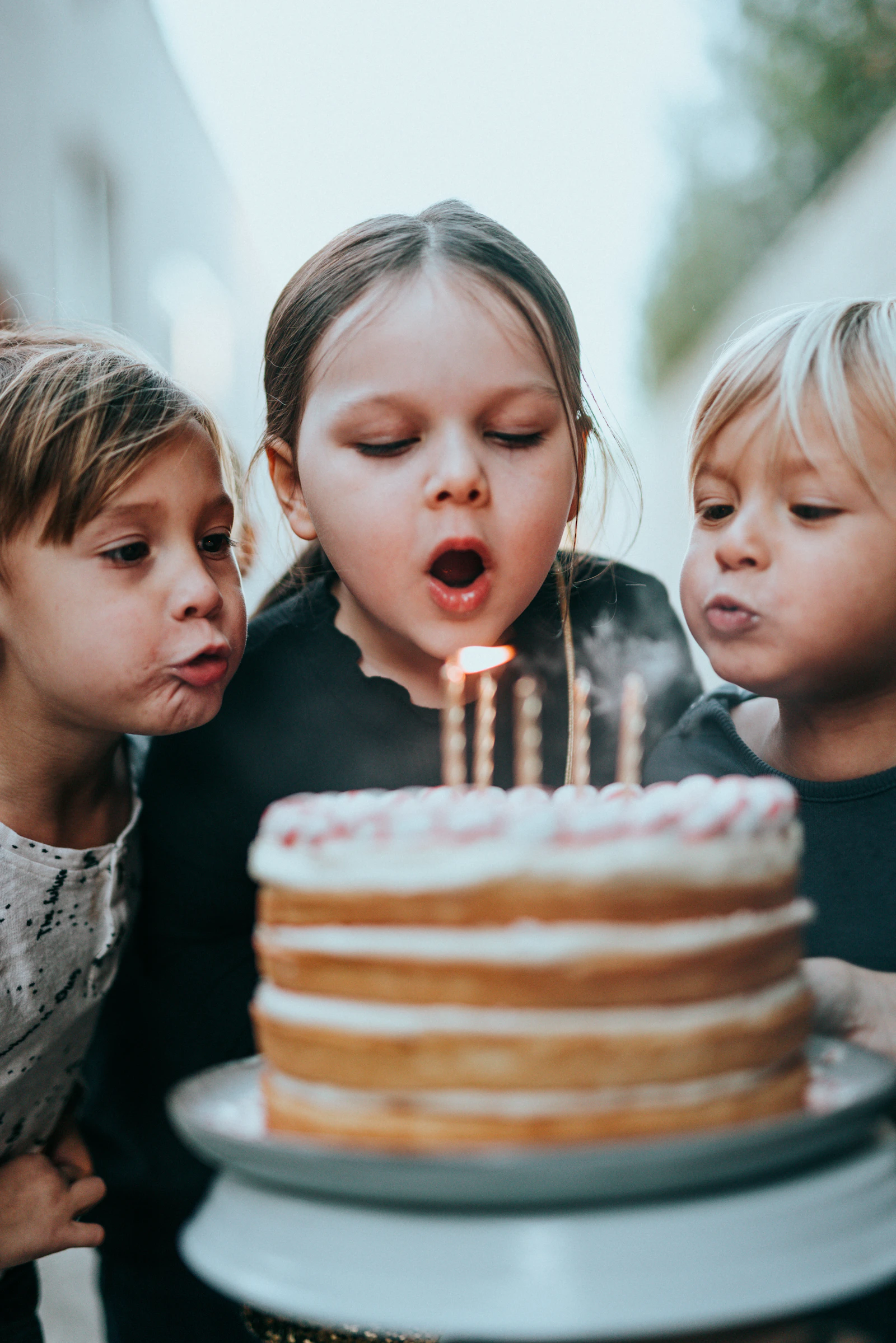 Un garçon et une fille soufflent ensemble les bougies d'un gâteau d'anniversaire.