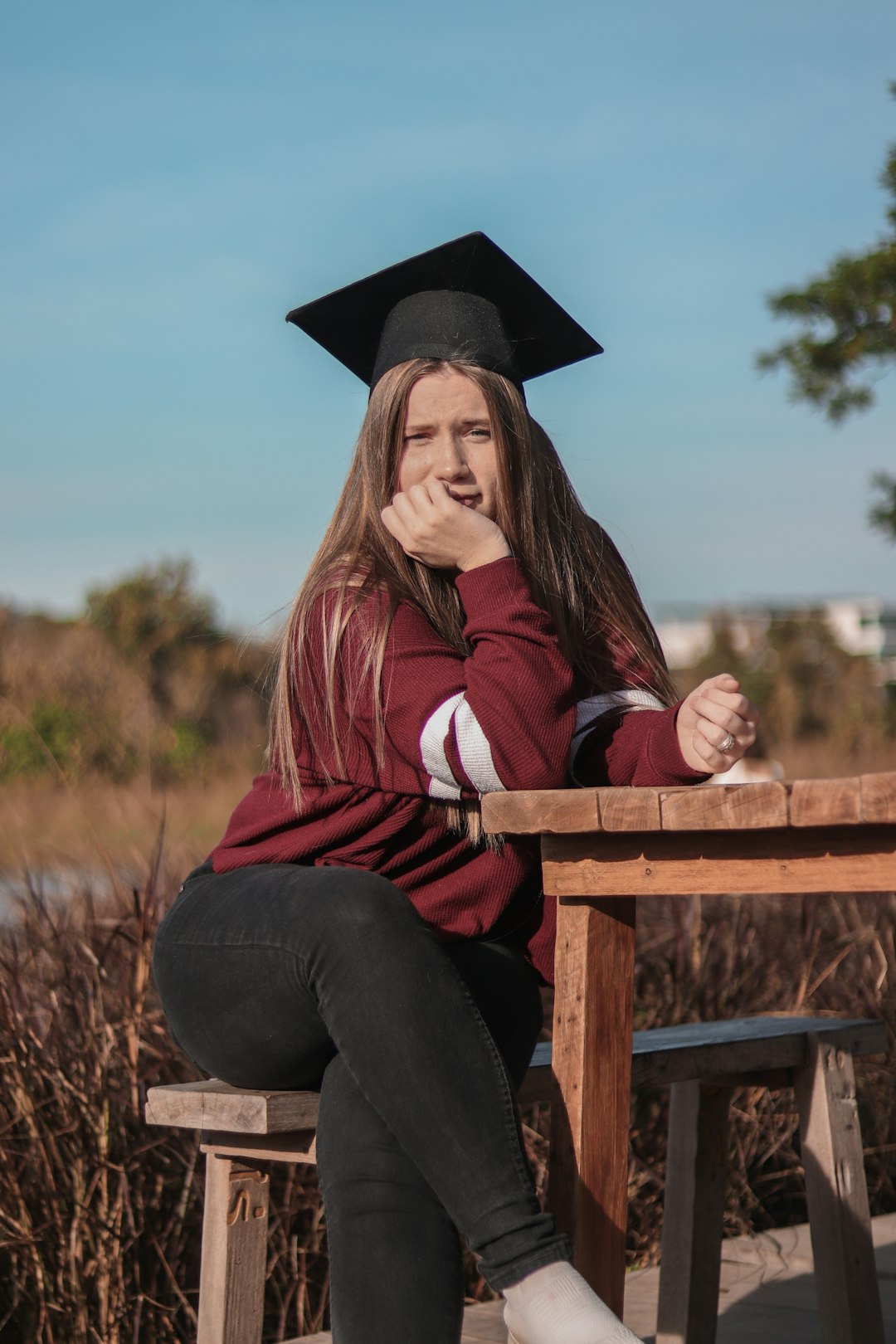 woman in red and white striped long sleeve shirt and black academic hat sitting on brown