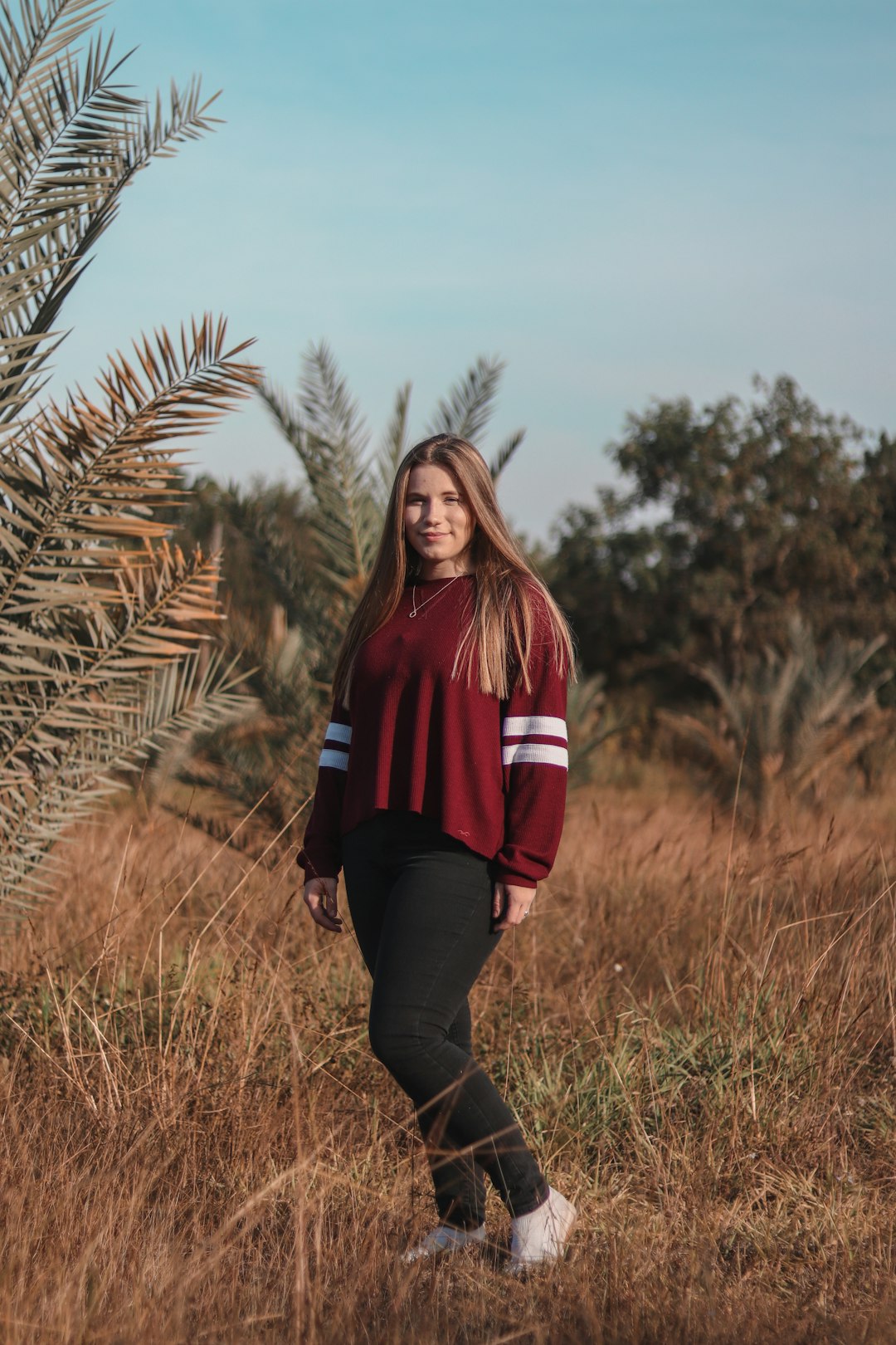 woman in red and black jacket standing on brown grass field during daytime