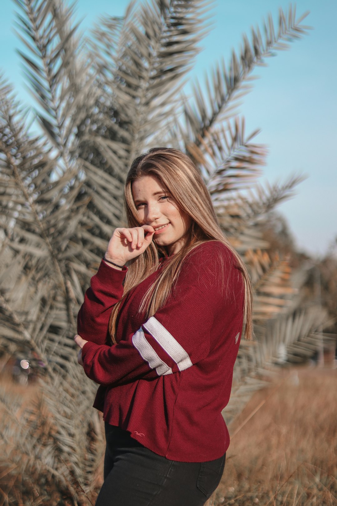 woman in red long sleeve shirt standing near brown trees during daytime