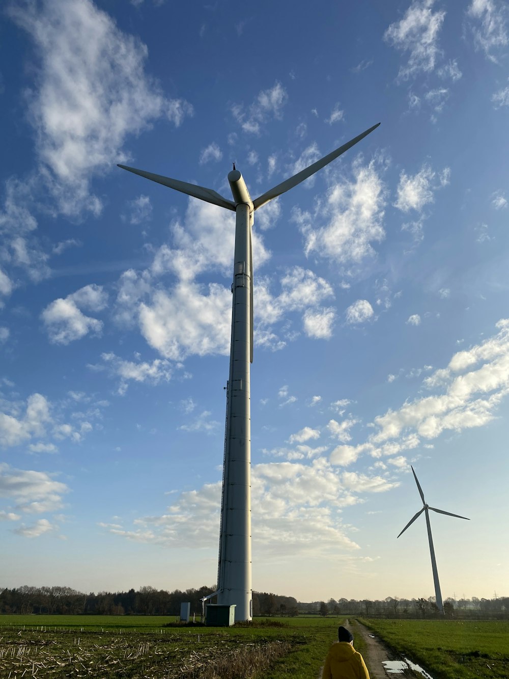 black wind turbine under blue sky and white clouds during daytime