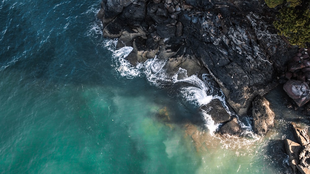 water waves hitting rocky shore during daytime