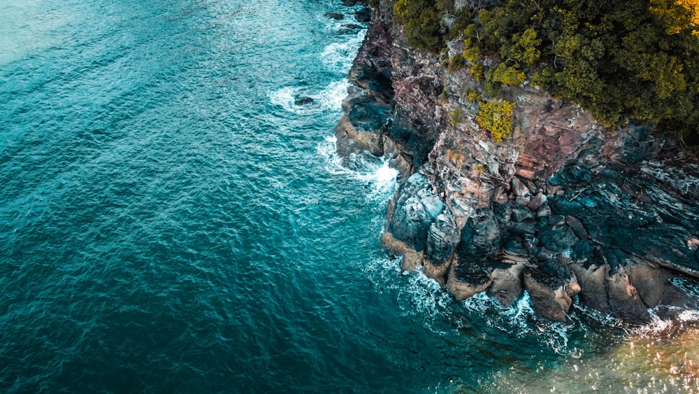 brown rocky mountain beside body of water during daytime