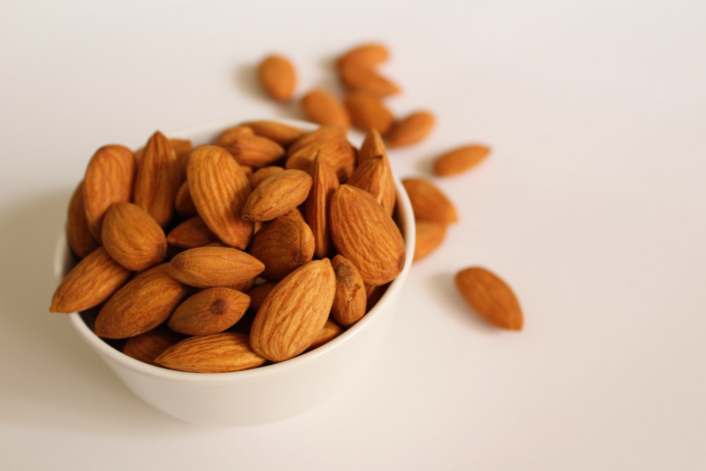 Noix d’amandes brunes sur bol en céramique blanche