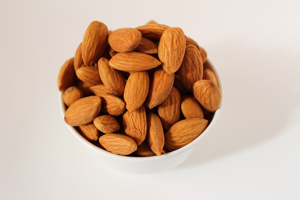 brown almond nuts on white ceramic bowl