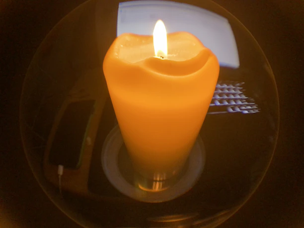 Close-up of a hand gently adjusting the 3D candle preview on a sleek laptop screen with soft pink tones in the background.