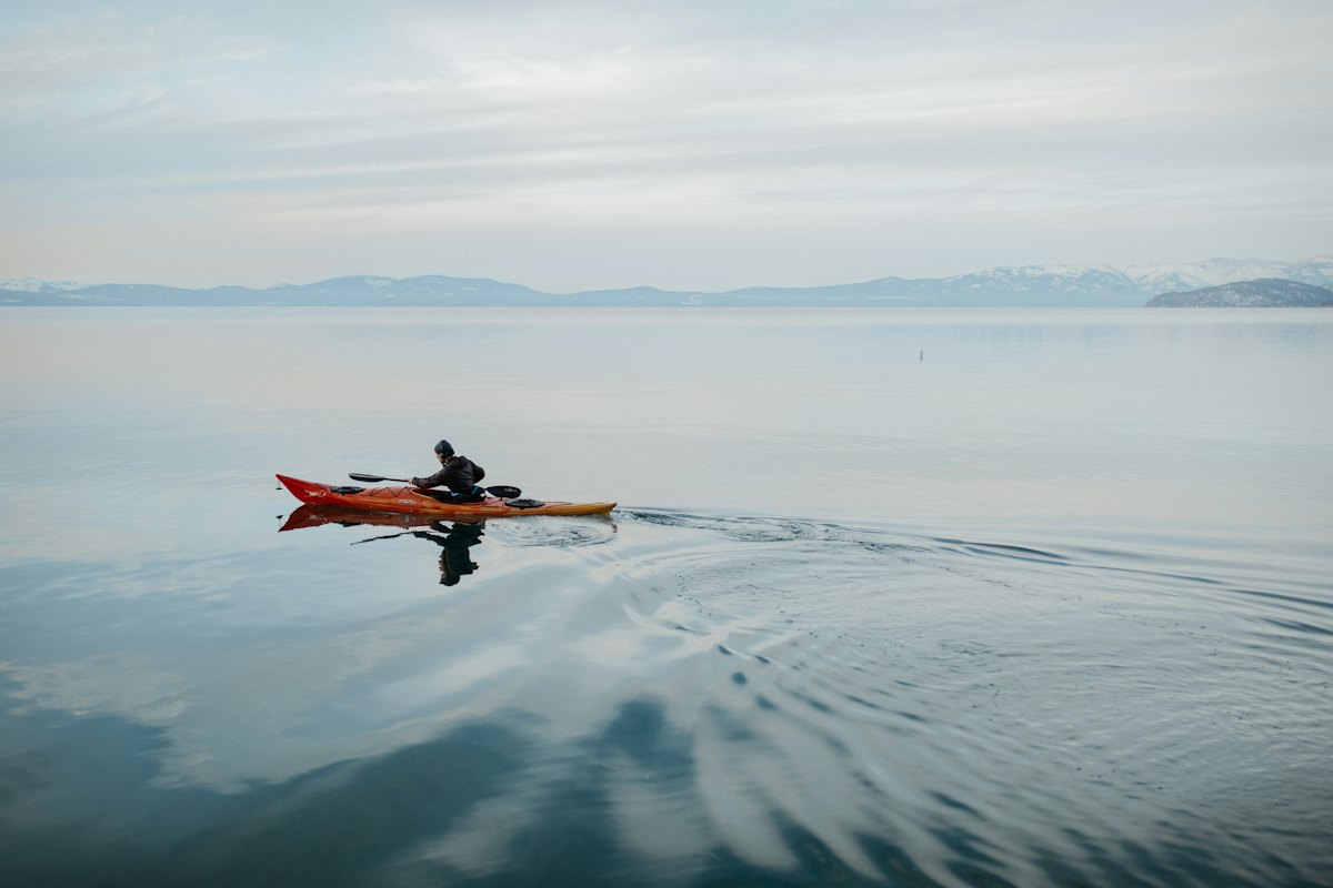 A kayaker gliding across a calm lake