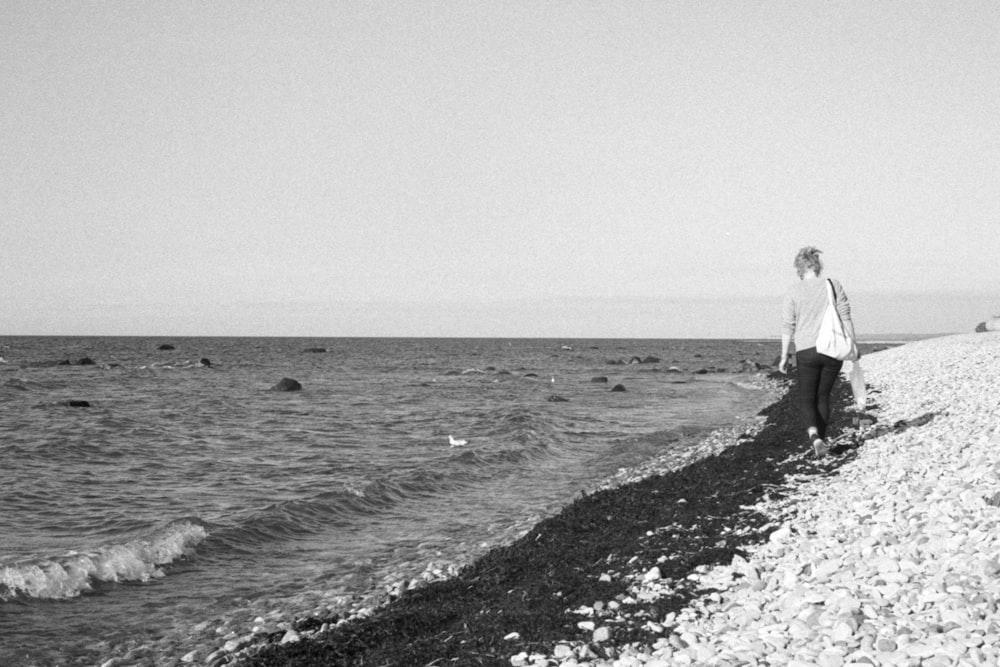 해변에서 걷는 남자와 여자의 그레이스케일 사진