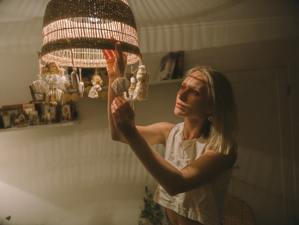 woman in white tank top holding gold and white pendant lamp