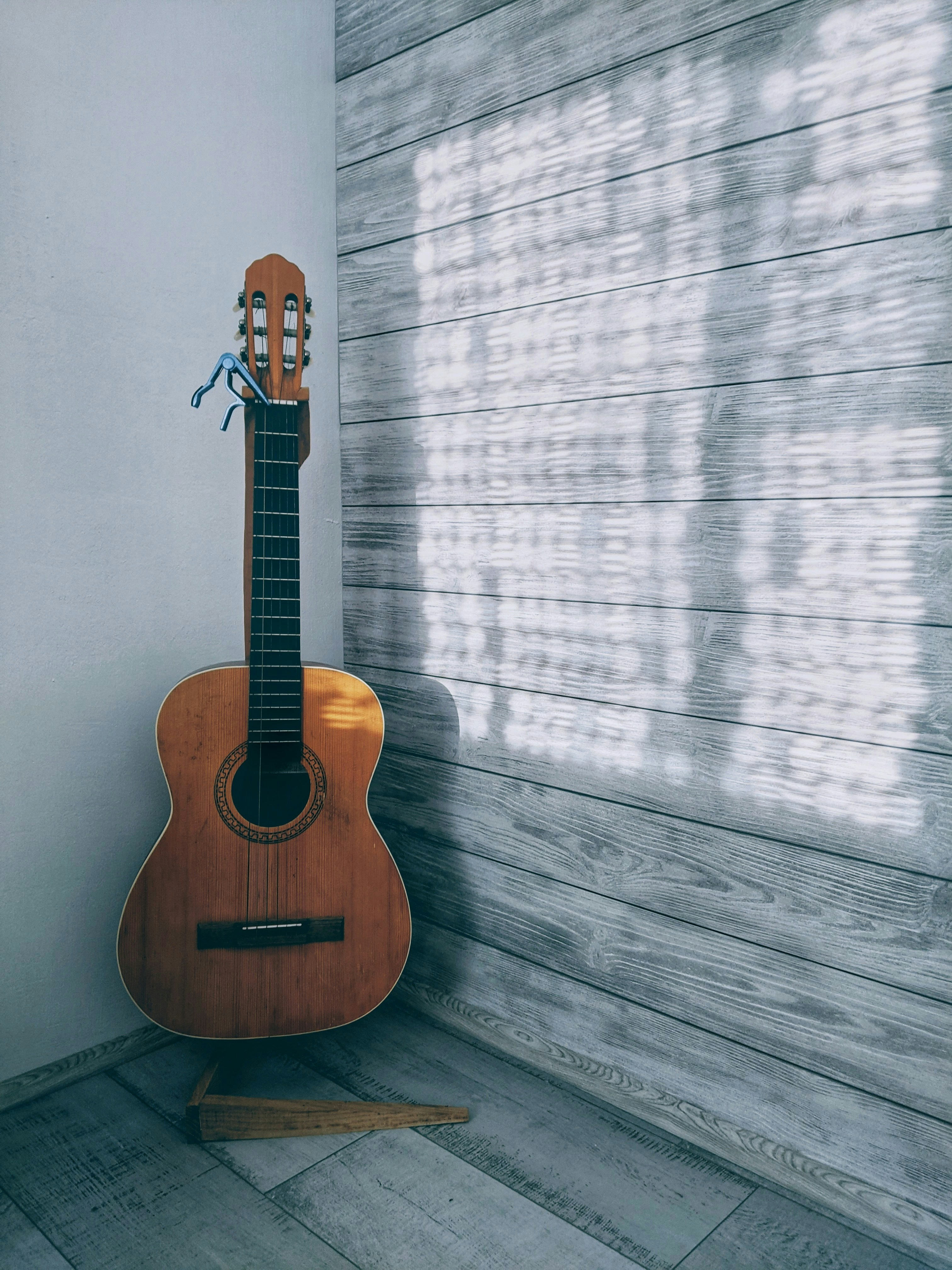 brown acoustic guitar on brown wooden floor