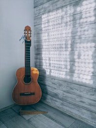brown acoustic guitar on brown wooden floor