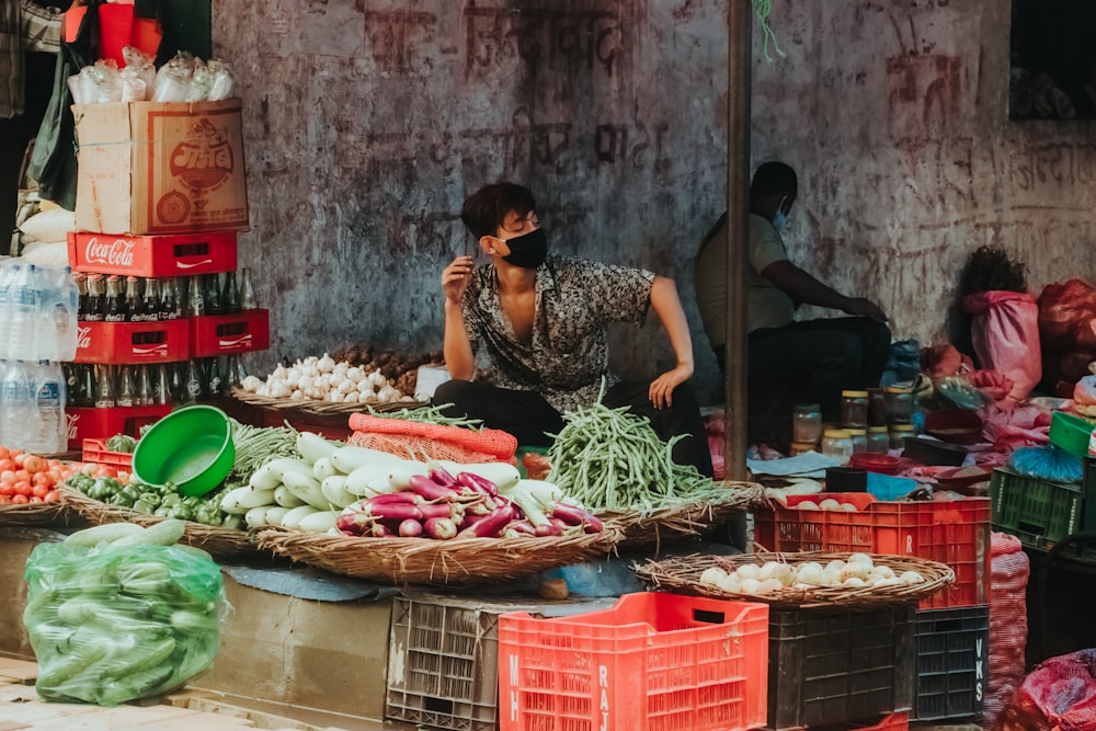 woman in black and white floral sleeveless dress standing in front of vegetable stand