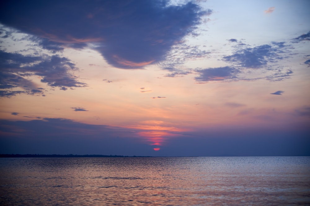 body of water under cloudy sky during sunset