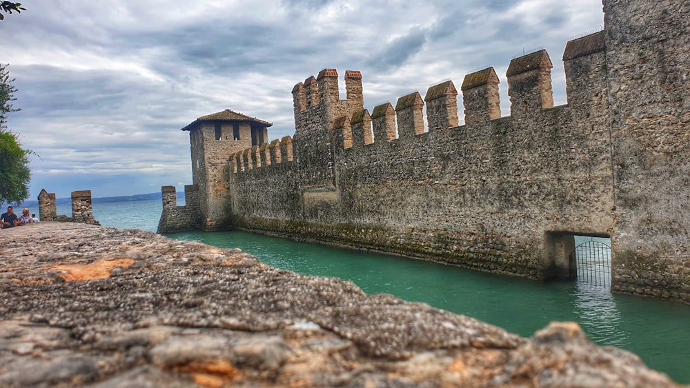 brown concrete building on green body of water under white clouds during daytime