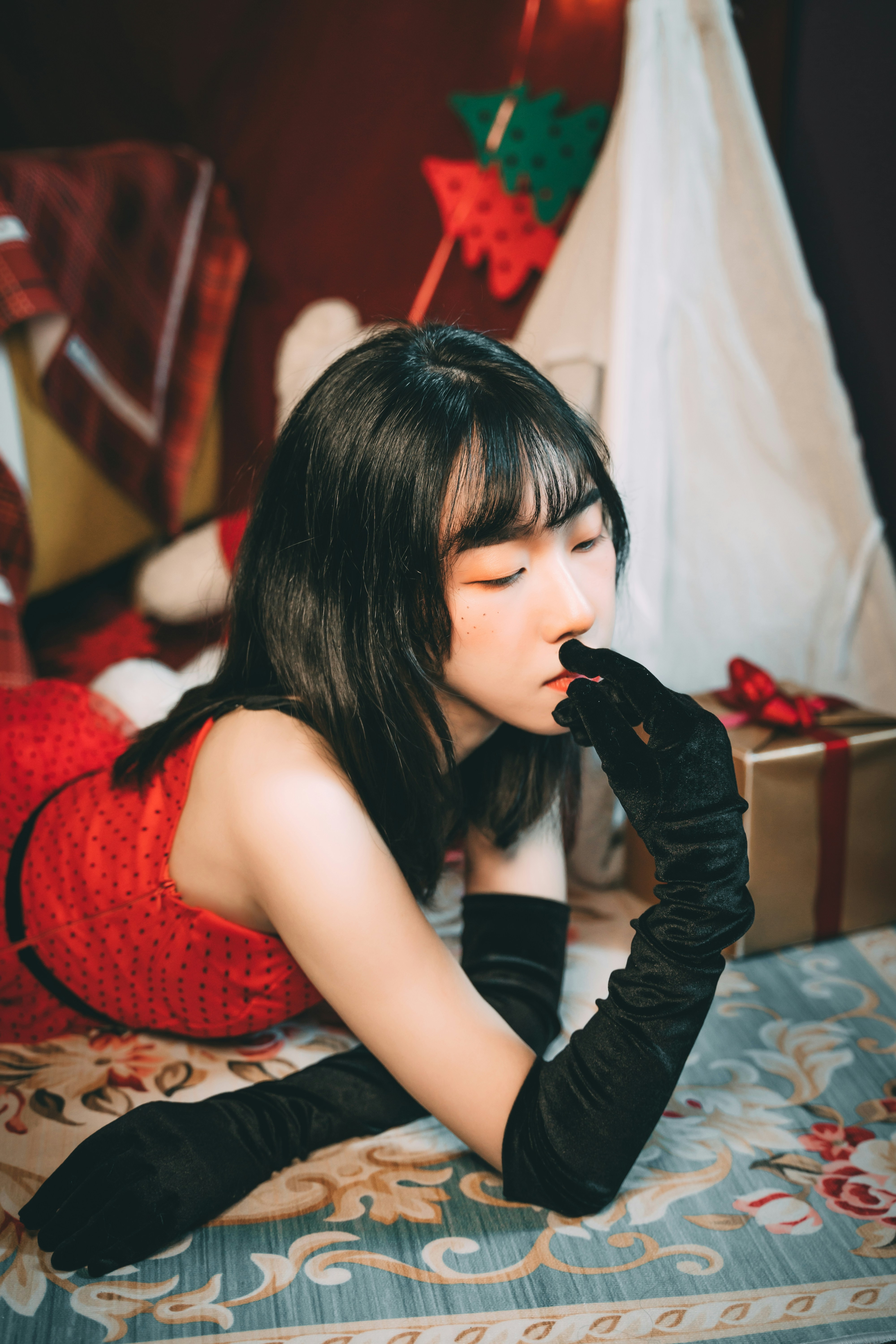 Wanita dengan gaun merah dan hitam duduk di tempat tidur