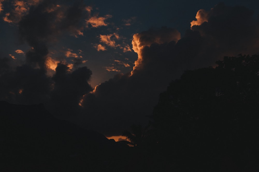silhouette of mountain under cloudy sky during night time