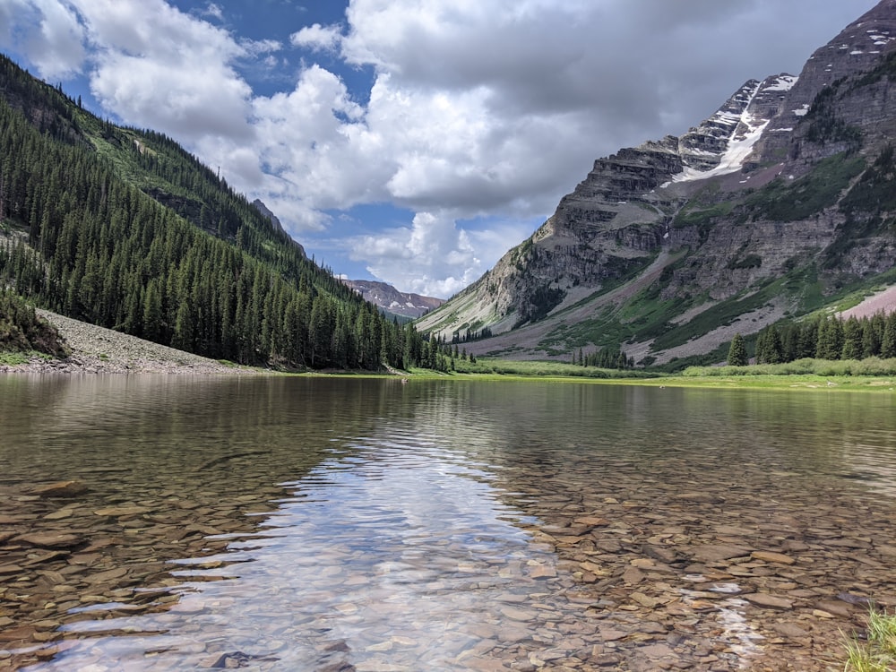 green and gray mountains beside river under white clouds and blue sky during daytime