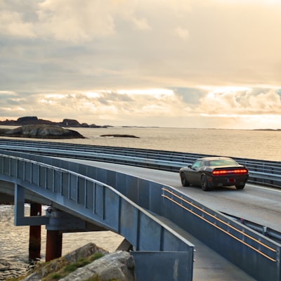 black suv on gray concrete bridge under gray cloudy sky during daytime