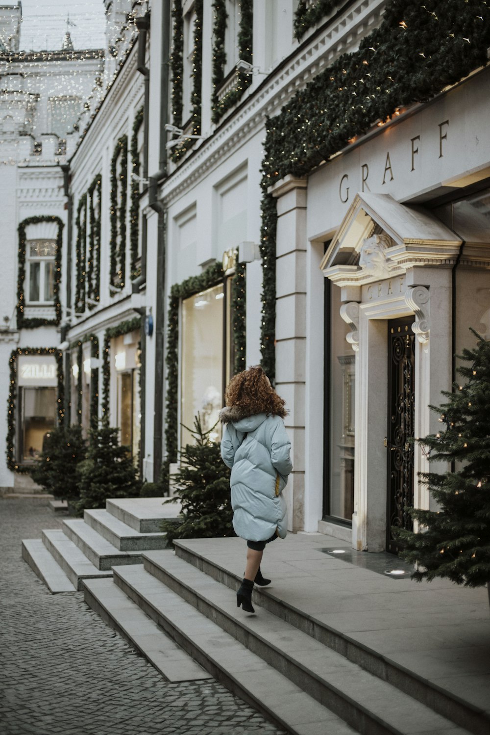 woman in gray coat walking on sidewalk during daytime