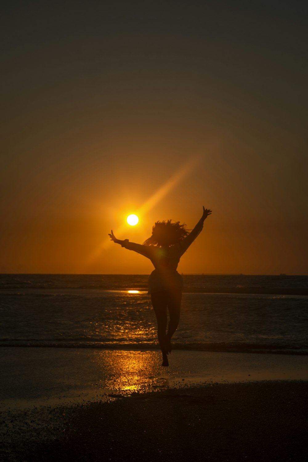 夕暮れ時の浜辺に立つ女性のシルエット