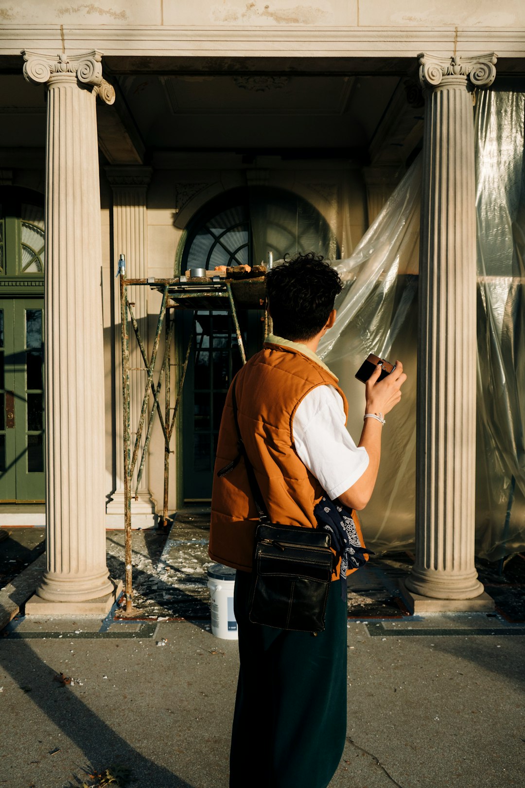 man in orange shirt and black backpack standing near glass window