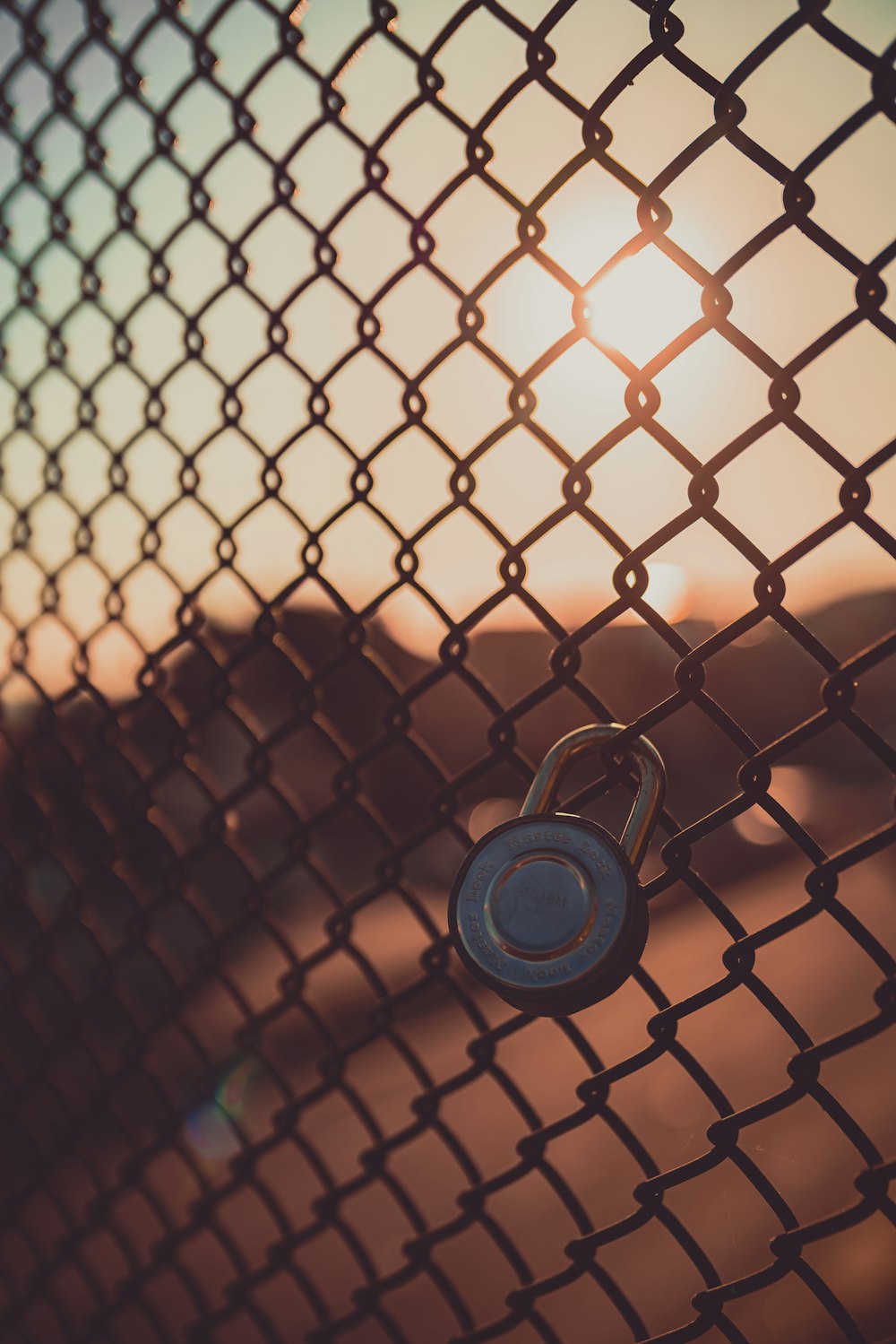 black and silver padlock on chain link fence
