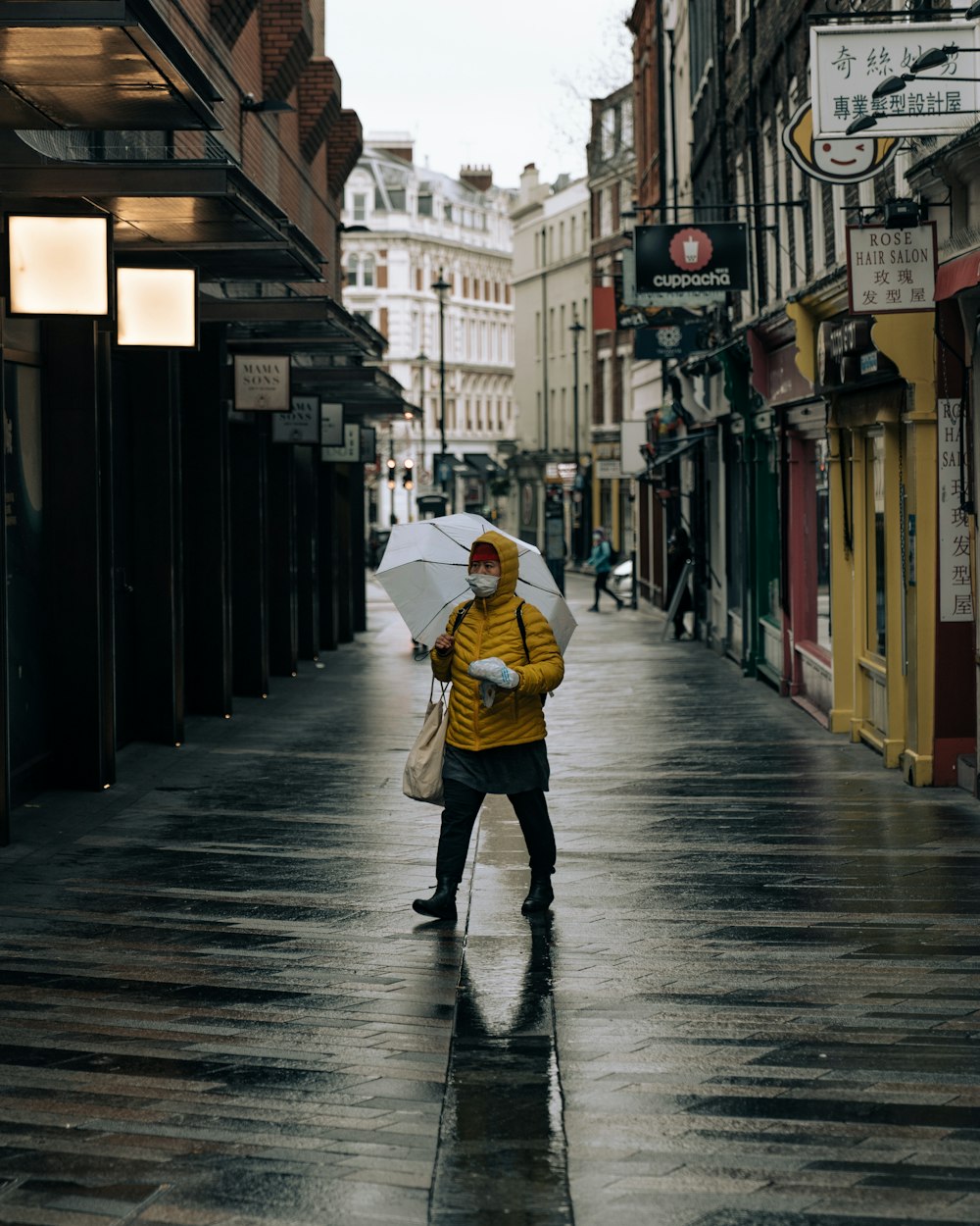 person in yellow jacket walking on sidewalk during daytime