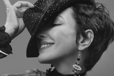 A smiling customer trying on a fashionable hat in front of a mirror.