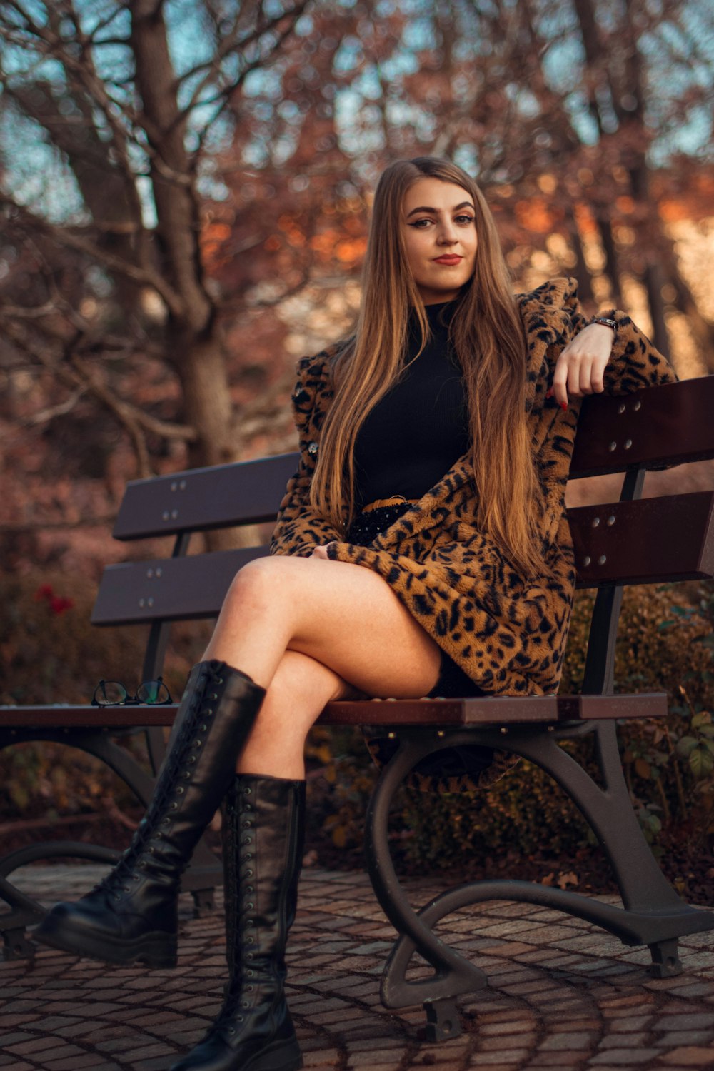 woman in black and yellow leopard print dress sitting on brown wooden bench
