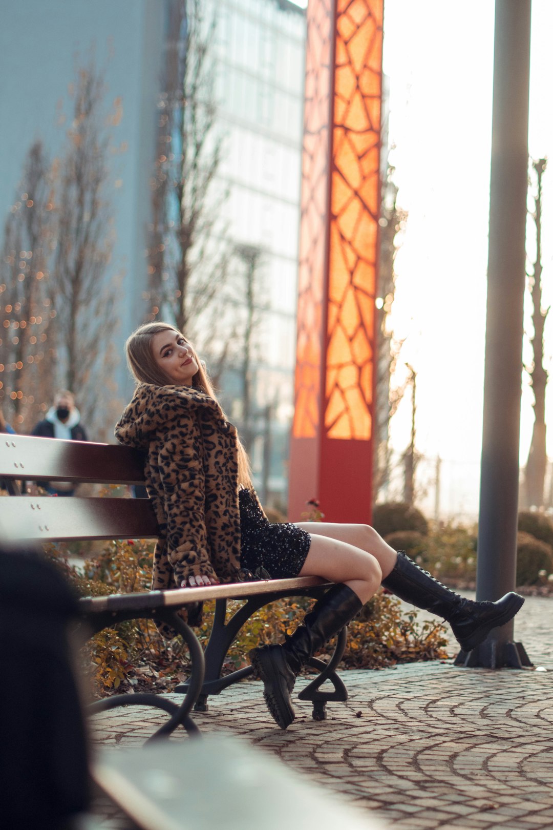 woman in brown and black leopard print coat sitting on brown wooden bench during daytime