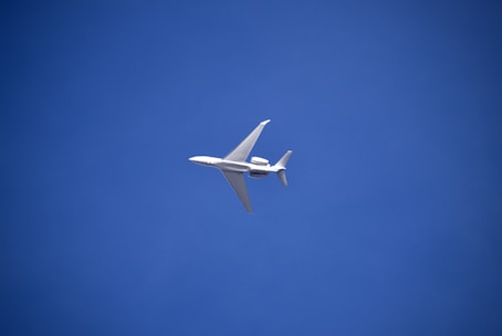 A modern airplane soaring through a clear blue sky.
