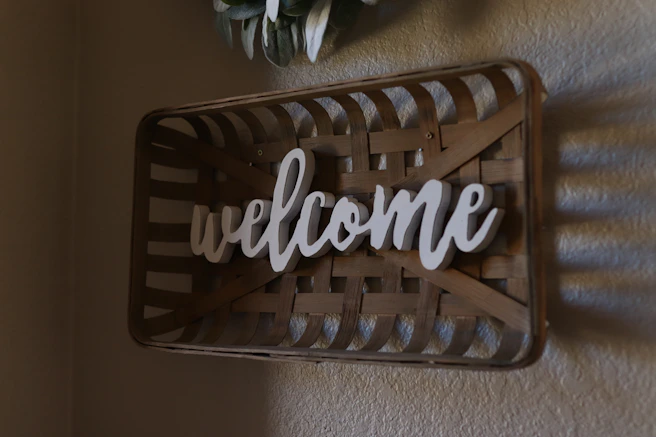 A friendly neighbor smiling while holding a welcome basket at the doorstep of a cozy home.