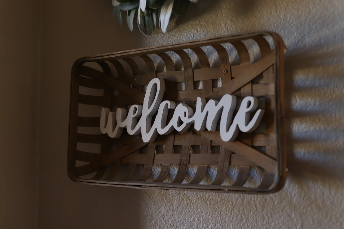A friendly neighbor smiling while holding a welcome basket at the doorstep of a cozy home.