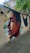 A detailed mural on a wall depicting a realistic side profile of a person with geometric shapes and vivid colors in the background. The mural is situated on a pedestrian walkway, surrounded by greenery and urban elements.