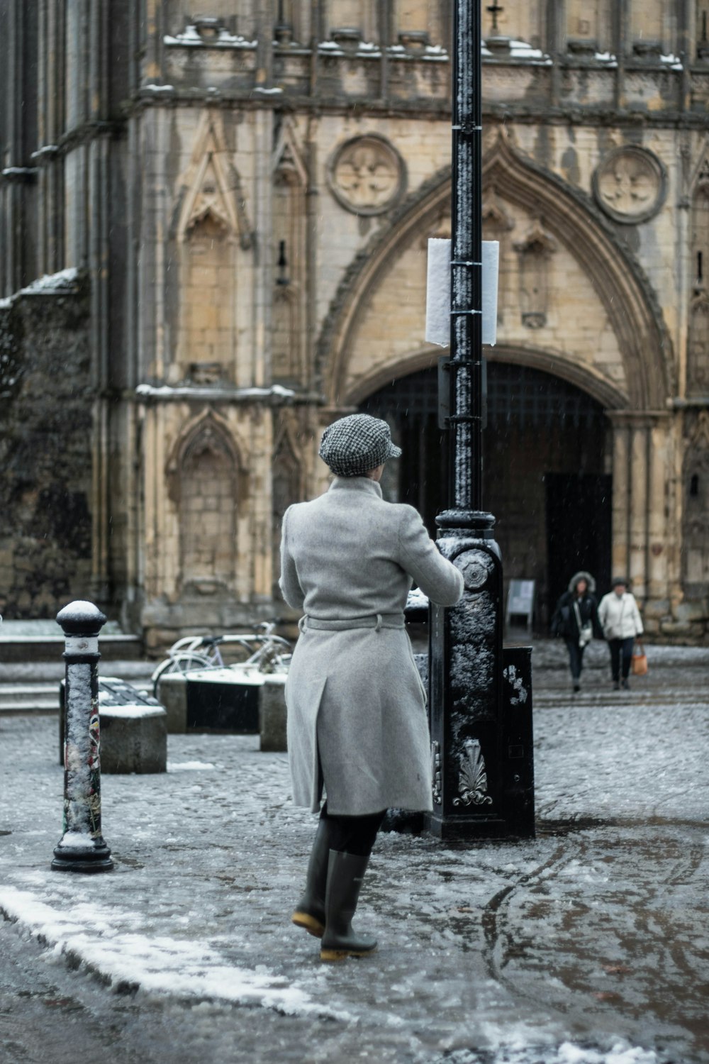 man in white coat standing near black metal post during daytime