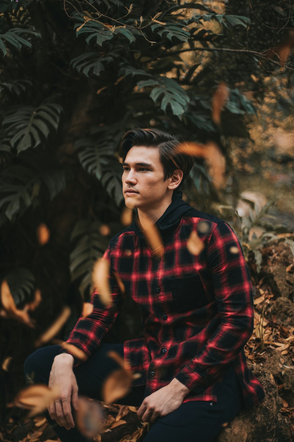 woman in red and black plaid dress shirt sitting on brown rock