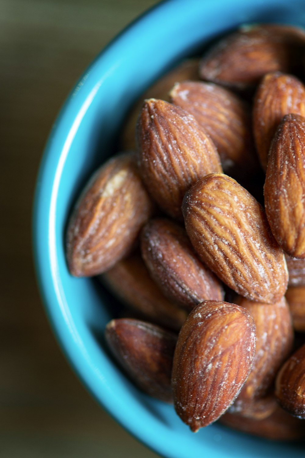 brown almond nuts on blue ceramic bowl