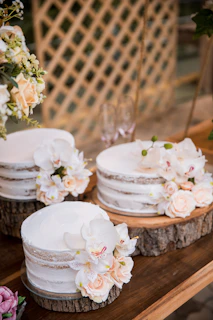 Elegant display of personalized cakes with floral decorations on a rustic wooden table.