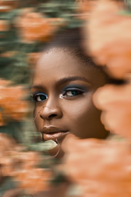 Close-up of glowing skin on a smiling woman in her 50s surrounded by floral elements.