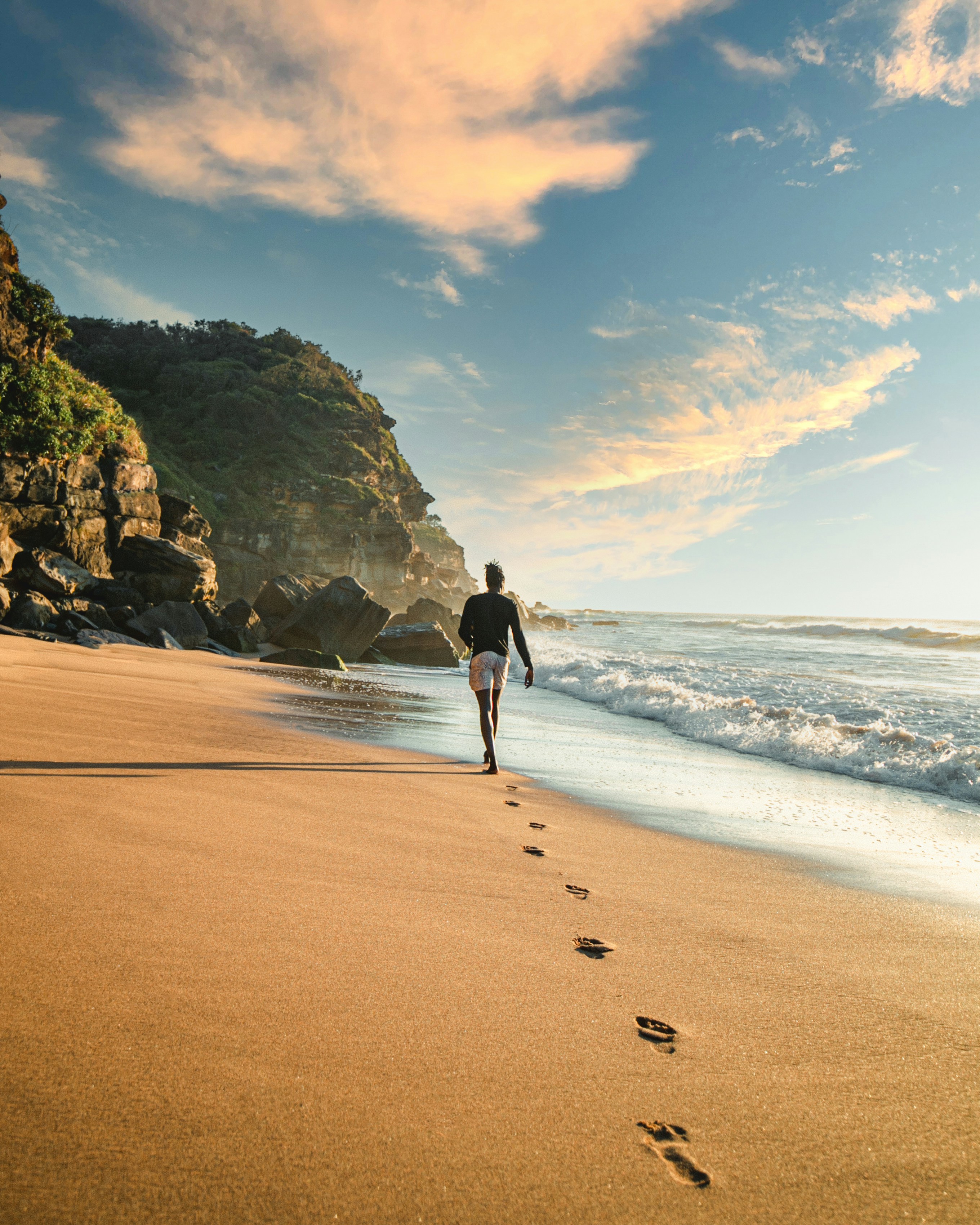 man in black jacket walking on seashore during daytime