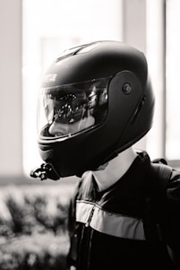 A rugged, dark-themed photo of a person wearing a helmet and a Driven Militia shirt, standing beside a sleek car at dusk.
