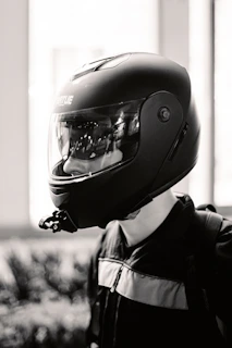 Dynamic black and white photo of a rider leaning into a curve wearing premium noirveloce gear against a blurred urban background.