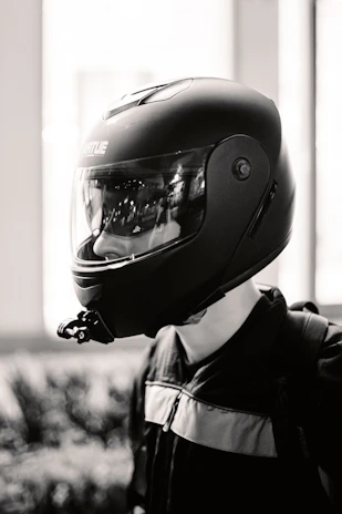 Dynamic black and white photo of a rider leaning into a curve wearing premium noirveloce gear against a blurred urban background.