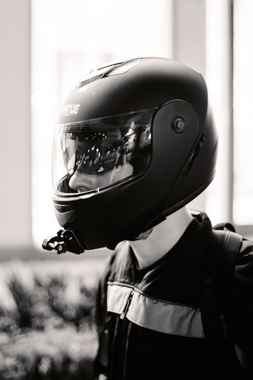 A rugged, dark-themed photo of a person wearing a helmet and a Driven Militia shirt, standing beside a sleek car at dusk.
